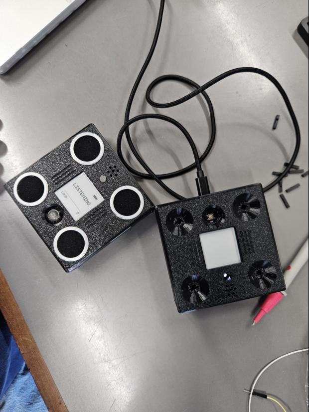 Two assembled VolAnti devices on a workbench with cables attached